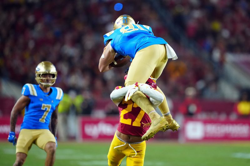 Nov 29, 2025; Los Angeles, California, USA; UCLA Bruins tight end Hudson Habermehl (81) is tackled by Southern California Trojans cornerback Alex Graham (27) in the first half at United Airlines Field at Los Angeles Memorial Coliseum. Mandatory Credit: Kirby Lee-Imagn Images