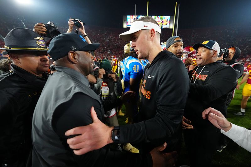 Nov 29, 2025; Los Angeles, California, USA; UCLA Bruins interim coach Tim Skipper (left) shakes hands with Southern California Trojans head coach Lincoln Riley after the game at United Airlines Field at Los Angeles Memorial Coliseum. Mandatory Credit: Kirby Lee-Imagn Images