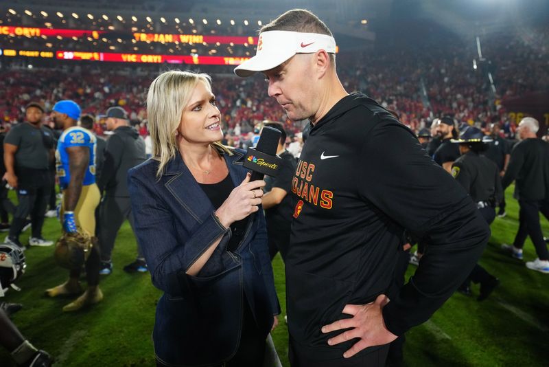 Nov 29, 2025; Los Angeles, California, USA; Southern California Trojans head coach Lincoln Riley (right) is interviewed by NBC Sports reporter Kathryn Tappen after the game against the UCLA Bruins at United Airlines Field at Los Angeles Memorial Coliseum. Mandatory Credit: Kirby Lee-Imagn Images