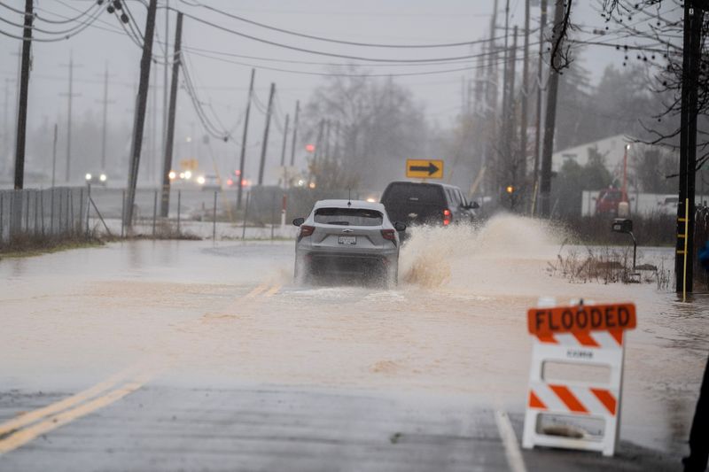 Cars drive through flooded waters on Westside Road in south Redding on Monday Morning, Dec. 22, 2025.