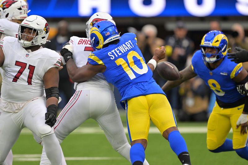 Jan 4, 2026; Inglewood, California, USA; Arizona Cardinals quarterback Jacoby Brissett (7) is strip sacked by Los Angeles Rams linebacker Josaiah Stewart (10) during the first half at SoFi Stadium. Mandatory Credit: Jayne Kamin-Oncea-Imagn Images