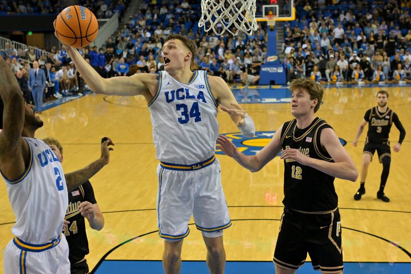 Jan 20, 2026; Los Angeles, California, USA; UCLA Bruins forward Tyler Bilodeau (34) beats Purdue Boilermakers center Daniel Jacobsen (12) to a rebound in the second half at Pauley Pavilion presented by Wescom Financial. Mandatory Credit: Jayne Kamin-Oncea-Imagn Images