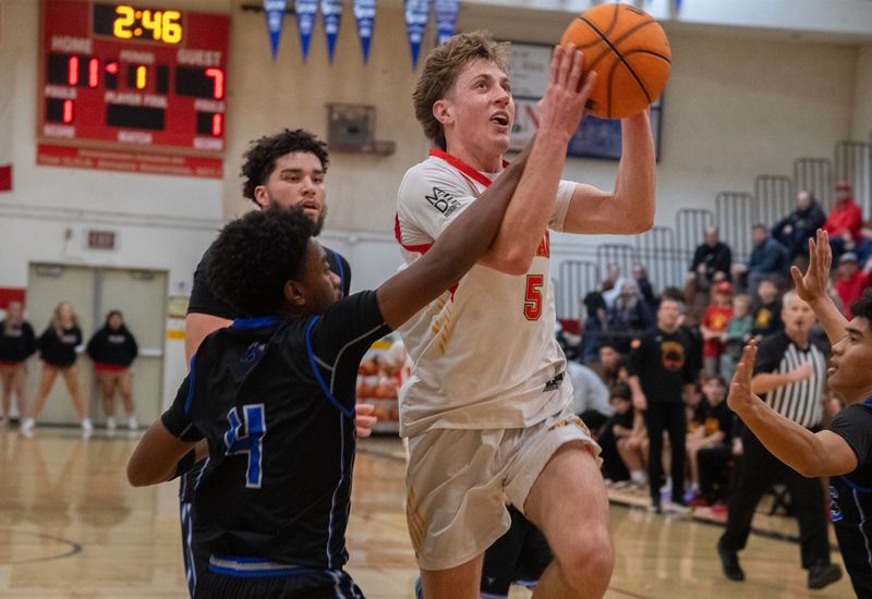 Oakdale’s Bryce Busam, right, goes the the hoop against Mountain House’s Braylon Major during a boys varsity basketball game at Oakdale High School in Oakdale on Jan. 21, 2026.