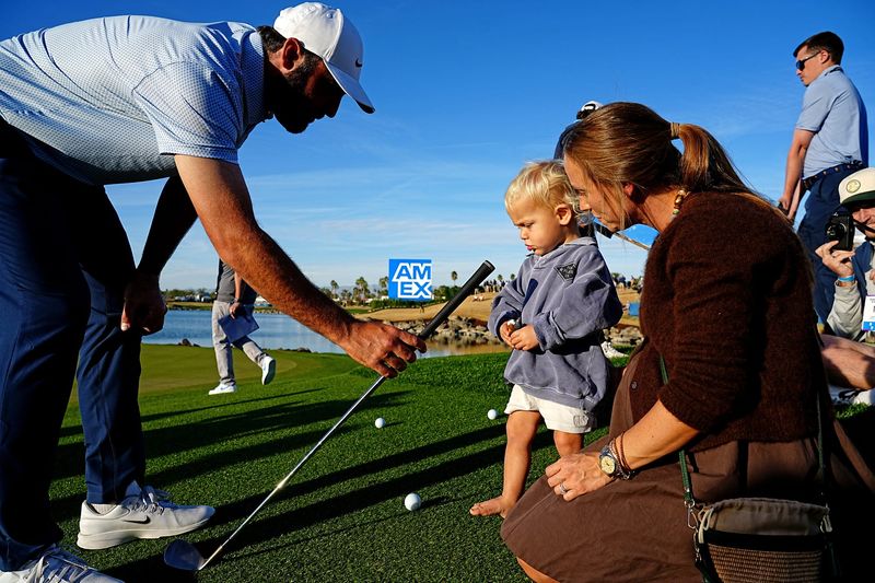 Scottie Scheffler offers his club to his son Bennett as wife Meredith looks on after winning the American Express at PGA West in La Quinta, Calif., on Sunday, Jan. 25, 2026.