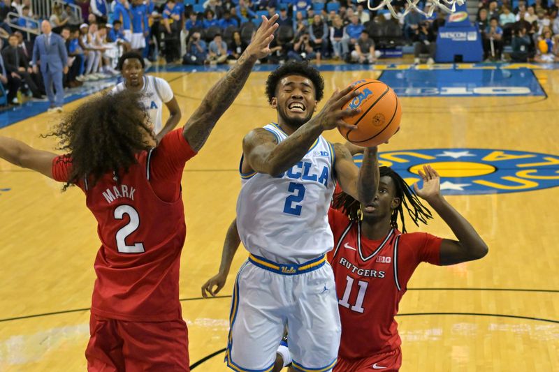 Feb 3, 2026; Los Angeles, California, USA; UCLA Bruins guard Donovan Dent (2) is defended by Rutgers Scarlet Knights guard Lino Mark (2) and Rutgers Scarlet Knights forward Chris Nwuli (11) as he drives for a basket in the first half at Pauley Pavilion presented by Wescom Financial. Mandatory Credit: Jayne Kamin-Oncea-Imagn Images