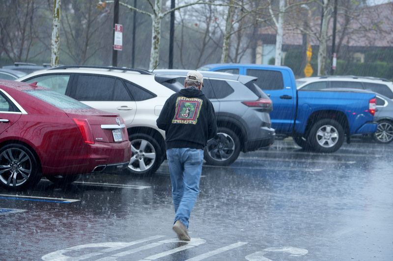 Horst Erichsen, of Westlake Village, walks back to his car in the rain at Gelson’s market in Westlake Village during a February storm.