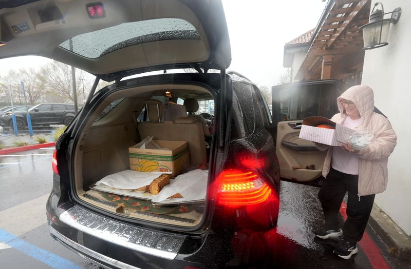 Mona Provencher, owner of Mamolo’s Fine Pastries inside Gelson’s in Westlake Village, parks her car in the rain to load pastries for a delivery on Feb. 16.