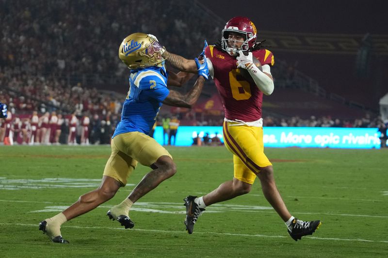 Nov 29, 2025; Los Angeles, California, USA; Southern California Trojans wide receiver Makai Lemon (6) carries the ball against UCLA Bruins defensive back Andre Jordan Jr. (2) in the second half at United Airlines Field at Los Angeles Memorial Coliseum. Mandatory Credit: Kirby Lee-Imagn Images