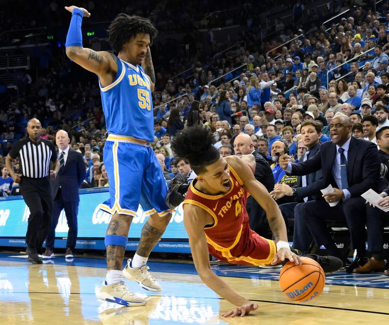 Feb 24, 2026; Los Angeles, California, USA; Southern California Trojans guard Chad Baker-Mazara (4) hits the floor as he tries to drive past UCLA Bruins guard Skyy Clark (55) during the first half at Pauley Pavilion presented by Wescom Financial. Mandatory Credit: Robert Hanashiro-Imagn Images