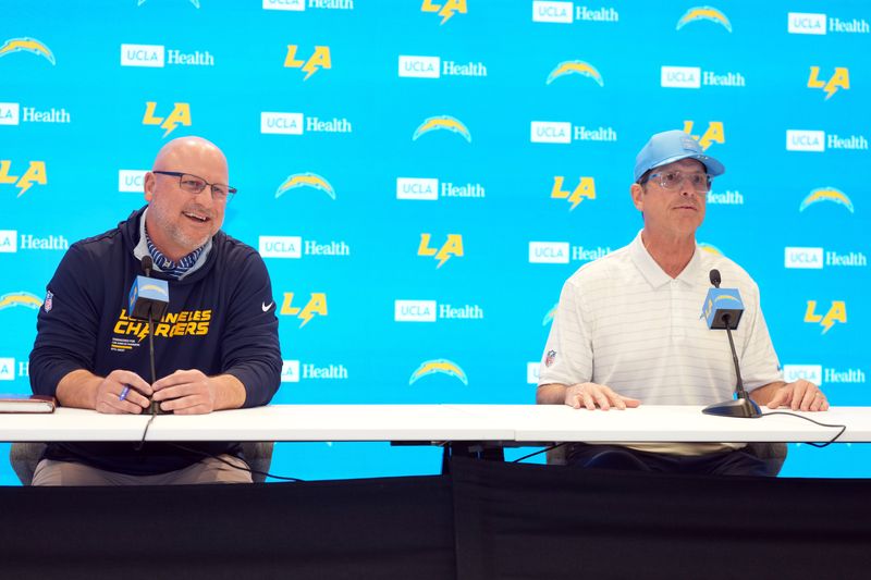 Jan 15, 2026; El Segundo, CA, USA; Los Angeles Chargers general manager Joe Hortiz (left) and coach Jim Harbaugh at press conference at The Bolt. Mandatory Credit: Kirby Lee-Imagn Images