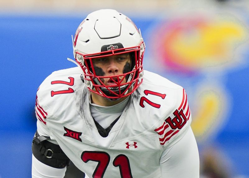 Utah Utes offensive lineman Caleb Lomu (71) gets ready before the snap during the second half against the Kansas Jayhawks at David Booth Kansas Memorial Stadium.
