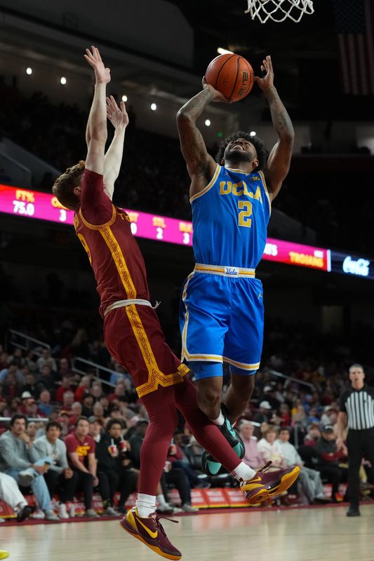Mar 7, 2026; Los Angeles, California, USA; UCLA Bruins guard Donovan Dent (2) shoots the ball against Southern California Trojans guard Ryan Cornish (9) in the first half at Galen Center. Mandatory Credit: Kirby Lee-Imagn Images