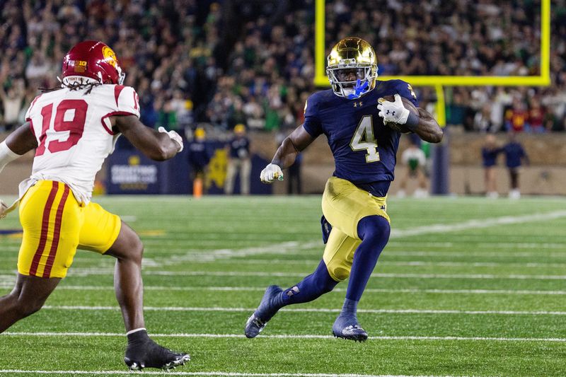 Oct 18, 2025; South Bend, Indiana, USA; Notre Dame Fighting Irish running back Jeremiyah Love (4) runs the ball while Southern California Trojans safety Bishop Fitzgerald (19) in the first half at Notre Dame Stadium. Mandatory Credit: Trevor Ruszkowski-Imagn Images