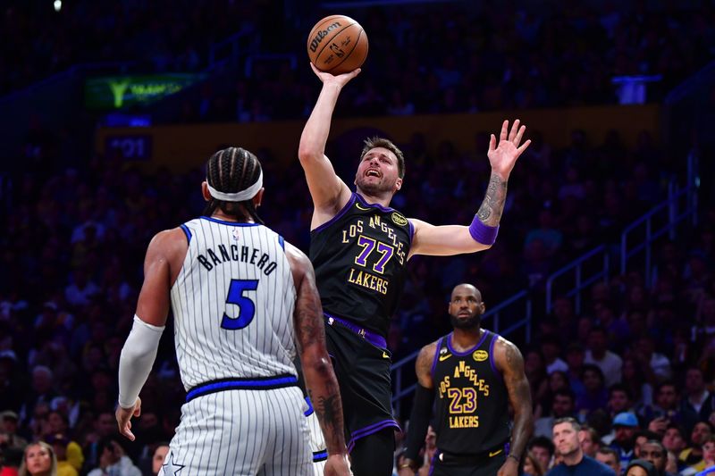 Feb 24, 2026; Los Angeles, California, USA; Los Angeles Lakers guard Luka Doncic (77) shoots against Orlando Magic forward Paolo Banchero (5) during the second half at Crypto.com Arena. Mandatory Credit: Gary A. Vasquez-Imagn Images
