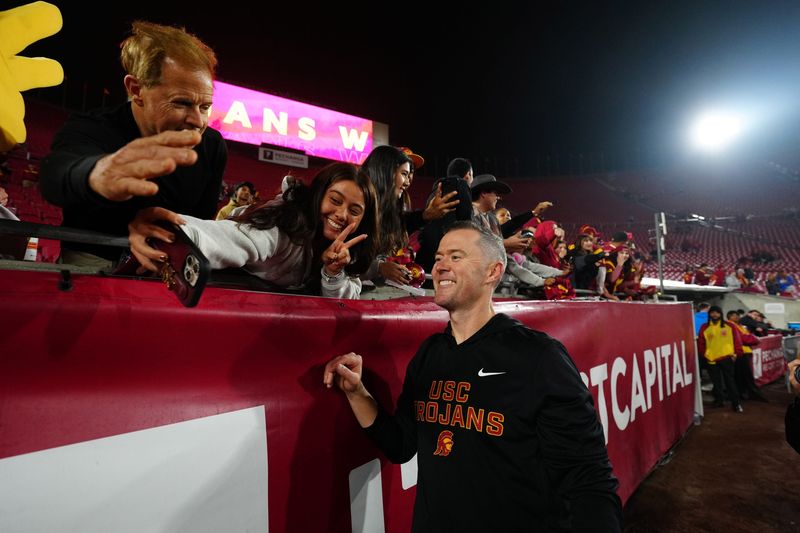 Nov 29, 2025; Los Angeles, California, USA; Southern California Trojans head coach Lincoln Riley celebrates with fans after the game against the UCLA Bruins at United Airlines Field at Los Angeles Memorial Coliseum. Mandatory Credit: Kirby Lee-Imagn Images