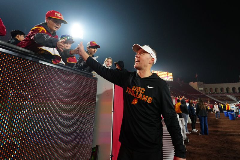 Nov 29, 2025; Los Angeles, California, USA; Southern California Trojans head coach Lincoln Riley celebrates with fans after the game against the UCLA Bruins at United Airlines Field at Los Angeles Memorial Coliseum. Mandatory Credit: Kirby Lee-Imagn Images