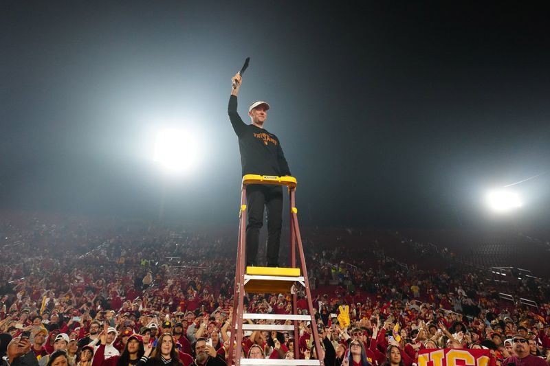 Nov 29, 2025; Los Angeles, California, USA; Southern California Trojans head coach Lincoln Riley leads the Spirit of Troy marching band in a rendition of Tribute to Troy after teh game against the UCLA Bruins at United Airlines Field at Los Angeles Memorial Coliseum. Mandatory Credit: Kirby Lee-Imagn Images