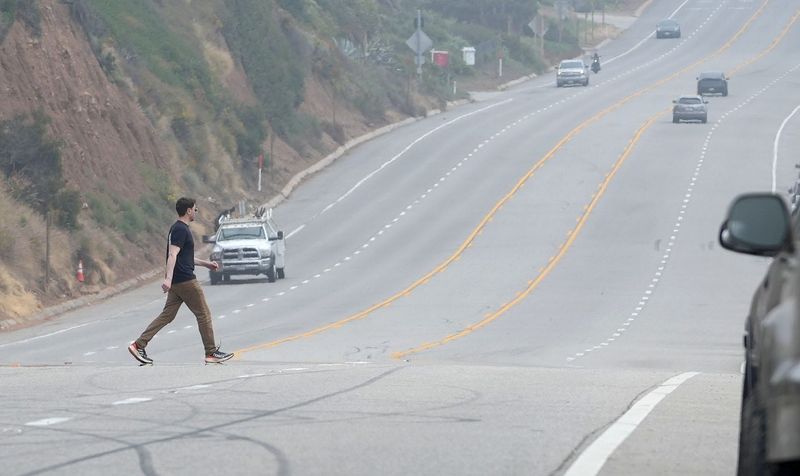 A pedestrian crosses Pacific Coast Highway near County Line Beach on March 23. The California Department of Transportation plans to install a crosswalk near the beach and Neptune's Net restaurant, just south of Yerba Buena Road.