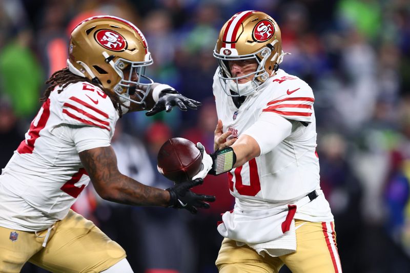 Jan 17, 2026; Seattle, WA, USA; San Francisco 49ers quarterback Mac Jones (10) hands off to running back Jordan James (29) against the Seattle Seahawks during the second half in an NFC Divisional Round game at Lumen Field. Mandatory Credit: Kevin Ng-Imagn Images