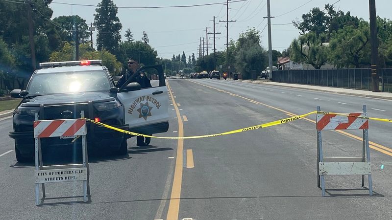 A California Highway Patrol officer stands near his parked cruiser where crime scene tape cordons off a Porterville street near an area where someone opened fire Tulare County Sheriff's deputies who were serving an eviction notice.