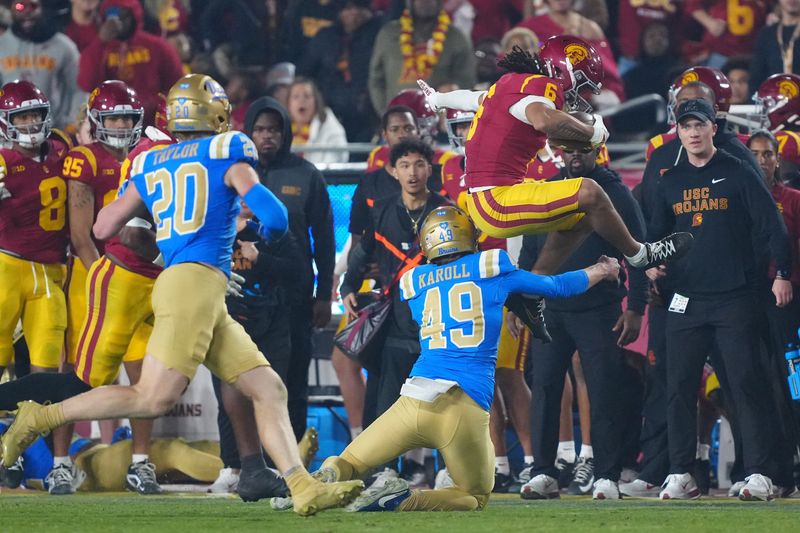 Nov 29, 2025; Los Angeles, California, USA; Southern California Trojans wide receiver Makai Lemon (6) hurdles UCLA Bruins punter Will Karoll (49) as linebacker Scott Taylor (20) watches in the second half at United Airlines Field at Los Angeles Memorial Coliseum. Mandatory Credit: Kirby Lee-Imagn Images