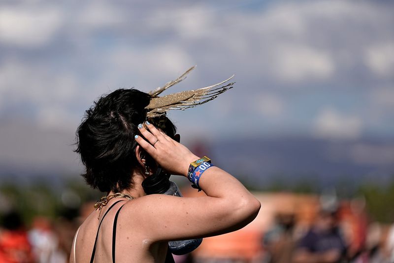 A festivalgoer holds on to a headpiece as the wind strengthens at the Coachella Valley Music and Arts Festival in Indio, Calif., on Friday, April 10, 2026.