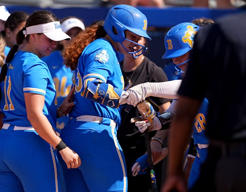 UCLA's Alexis Ramirez (28) helps Megan Grant (43) touch home plate after a home run in the 7th inning of the Women's College World Series softball game between the UCLA Bruins and the Tennessee Volunteers at Devon Park in Oklahoma City, Sunday, June, 1, 2025.