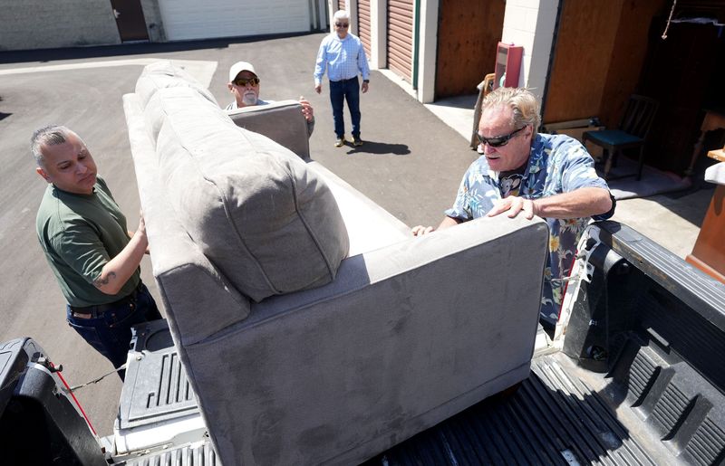 Volunteers Eddie Cabrera, from left, Gregg Kravitz and Roy Foster load up furniture into Paul Diaz's truck at a Ventura storage facility April 27.