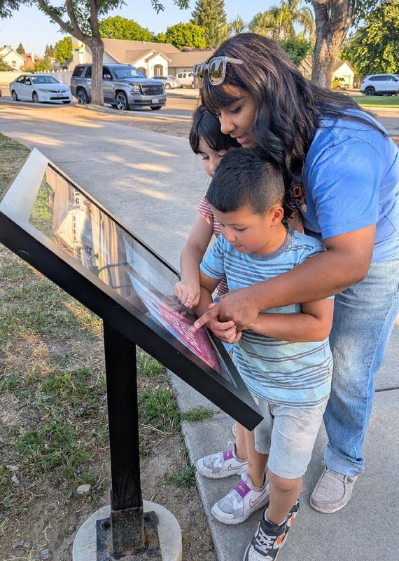 Sara Ray and her two children, Hannah and Benjamin, read and walk at Stonebrook Park in Visalia.