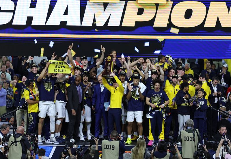 Apr 6, 2026; Indianapolis, IN, USA; Michigan Wolverines head coach Dusty May celebrates with the trophy after defeating the UConn Huskies in the national championship of the Final Four of the men's 2026 NCAA Tournament at Lucas Oil Stadium. Mandatory Credit: Trevor Ruszkowski-Imagn Images
