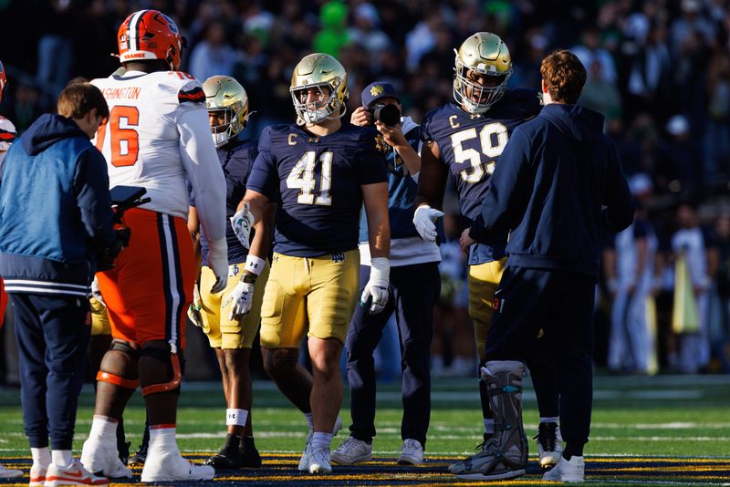 Former Notre Dame quarterback and current Syracuse quarterback Steve Angeli, right, greets Notre Dame offensive lineman Aamil Wagner (59) at the coin toss before a NCAA football game at Notre Dame Stadium on Saturday, Nov. 22, 2025, in South Bend.