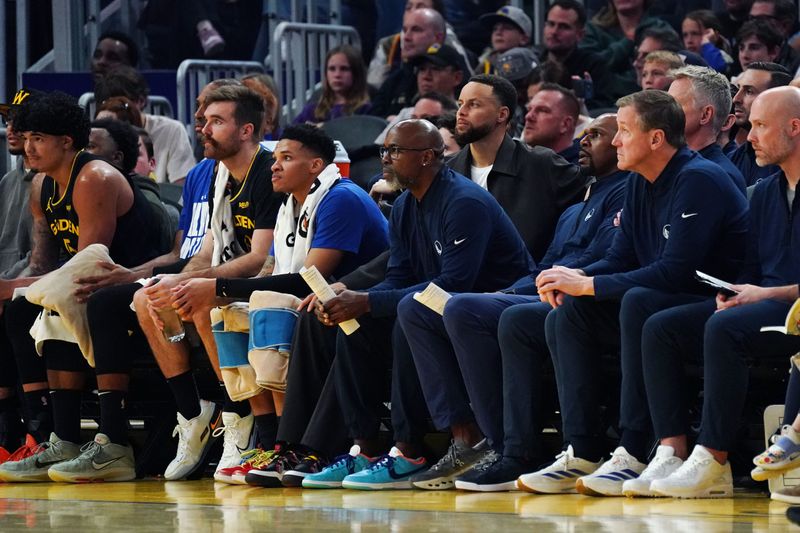 Feb 22, 2026; San Francisco, California, USA; Golden State Warriors assistant coach Kris Weems watches the action while sitting between guard Stephen Curry (30) and assistant coach Jerry Stackhouse in the second quarter against the Denver Nuggets at Chase Center. Mandatory Credit: David Gonzales-Imagn Images
