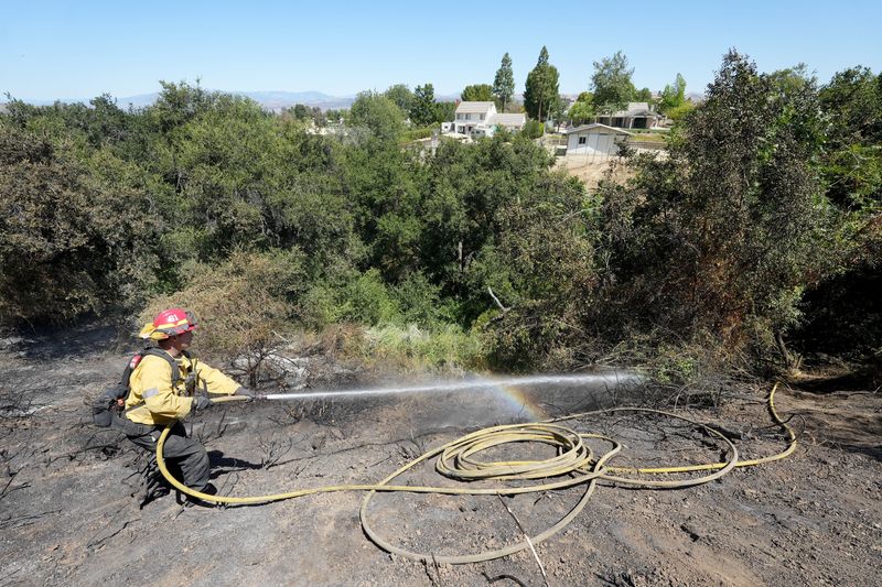 Capt. Richard Martinez with the Los Angeles Fire Department hoses down hot spots in Simi Valley during the Sandy Fire on May 19, 2026.