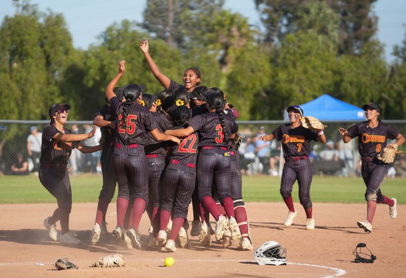 The Oxnard softball team swarms around pitcher Destinee Herrera (24) in the circle after the final out in a 5-4 extra innings win over St. Bonaventure in the CIF-Southern Section Division 4 softball quarterfinals May 20, 2026, at Ventura College.