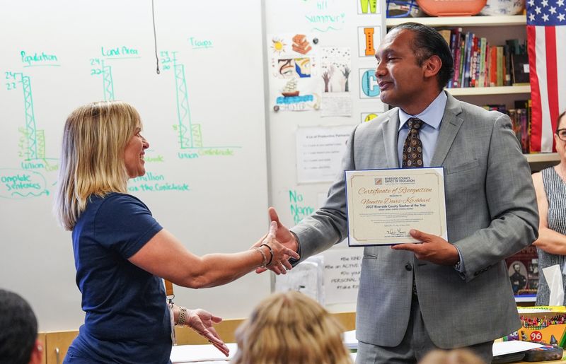 Nanette Davis-Kirchhevel of Palm Desert Charter Middle School, left, is surprised in her classroom May 21 by being named one of the Riverside County Office of Education’s Teachers of the Year. At right is Riverside County Superintendent of Schools Edwin Gomez.