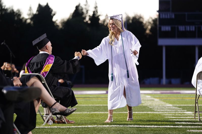 Shasta High School's Natalie Cooper fist bumps English teacher, Andy Kane, after receiving her diploma during the 127th annual commencement exercises at Thompson Field on campus. The Redding school awarded diplomas to 311 seniors during the graduation ceremony on Friday, June 5, 2026.