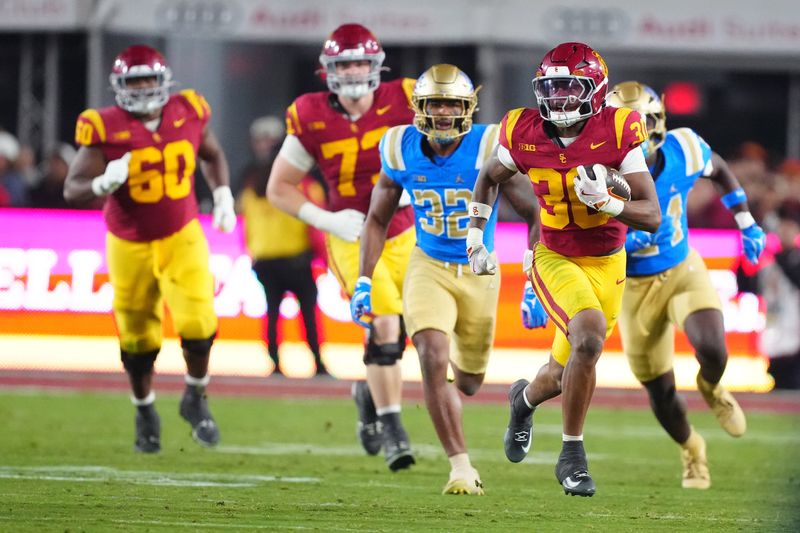 Nov 29, 2025; Los Angeles, California, USA; Southern California Trojans running back King Miller (30) carries the ball against UCLA Bruins linebacker Isaiah Chisom (32) in the first half at United Airlines Field at Los Angeles Memorial Coliseum. Mandatory Credit: Kirby Lee-Imagn Images