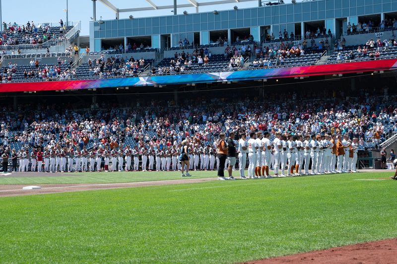 Jun 15, 2026; Omaha, NE, USA; Players line up for the national anthem before the game between the Alabama Crimson Tide and the Texas Longhorns at Charles Schwab Field. Mandatory Credit: Steven Branscombe-Imagn Images