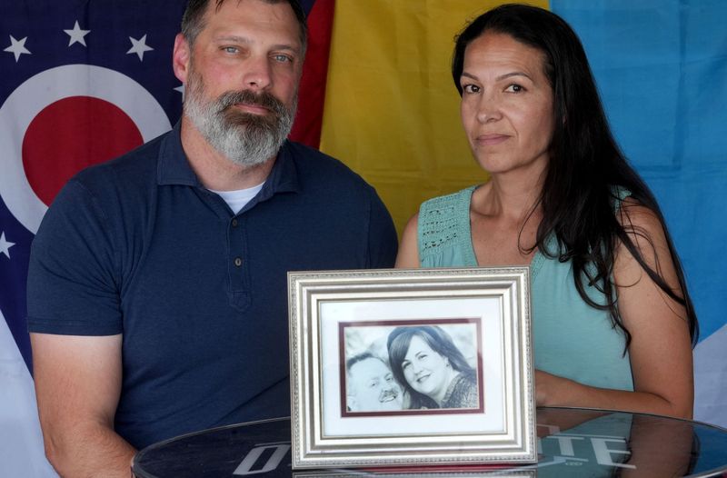 JD Patton and his wife Elena Patton, of Camarillo, share a framed photo of their late neighbors Albert and Linda Wolfkiel on June 17. The Pattons said they would care for the Wolfkiel's three children if anything happened to them and kept their promise when Albert and Linda died within months of each other.