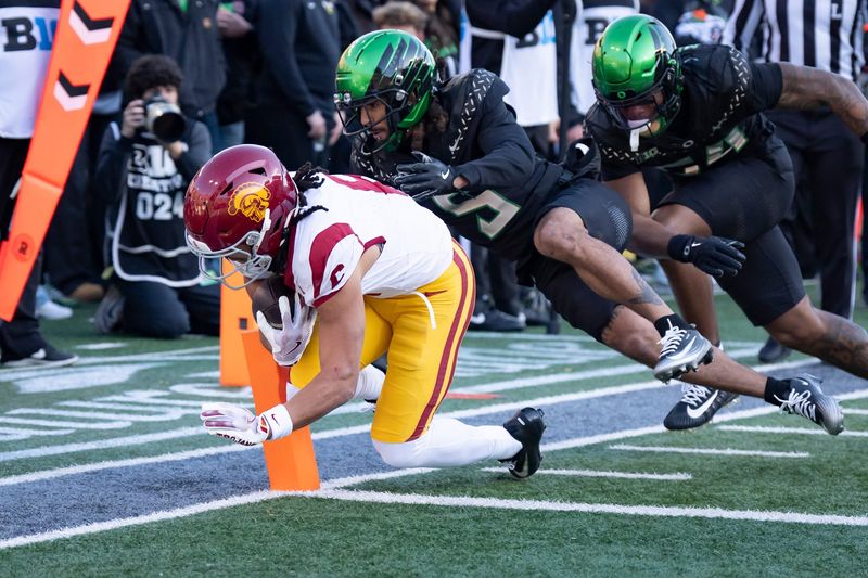 USC wide receiver Makai Lemon, left, dives into the corners of the end zone for a touchdown under cover from Oregon defensive back Theran Johnson as the Oregon Ducks host the USC Trojans on Nov. 22, 2025, at Autzen Stadium in Eugene, Oregon.