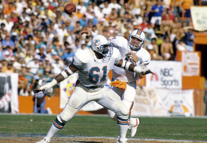 Jan 4, 1986; Miami, FL, USA; FILE PHOTO; Miami Dolphins guard Roy Foster (61) protects quarterback Dan Marino (13) during the 1985 AFC Divisional Playoff Game against the Cleveland Browns at the Orange Bowl. The Dolphins won 24-21. Mandatory Credit: Manny Rubio-USA TODAY Sports