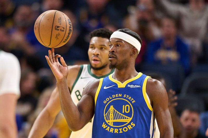 Jan 7, 2026; San Francisco, California, USA; Golden State Warriors forward Jimmy Butler III (10) spins the ball on his finger and Milwaukee Bucks forward Giannis Antetokounmpo (34) looks on during a stoppage of play in the third quarter at Chase Center. Mandatory Credit: Robert Edwards-Imagn Images