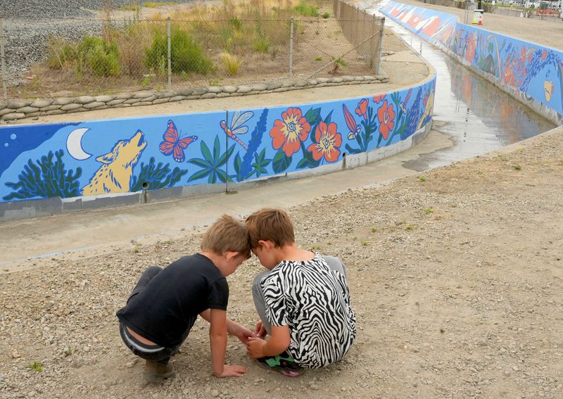 Chafik Lewis, from left, 6, and his brother Mounir Lewis, 8, of Ventura, play at the site of the Moon Ditch Mural — one of the largest murals in the United States — on June 27. Spanning nearly 3,400 linear feet along the Leland Street flood control channel in Ventura and visible from southbound Highway 101, the mural was designed by Oxnard artist Elisa Torres and created in collaboration with seven local artists and approximately 200 community volunteers.