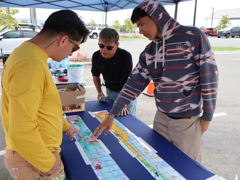 Jose Ortiz, artistic director of Hijo Del Sol Arts Productions, with (l-r) Josue David Rubio and Angel Hernandez as they review the mock-up of the mural going up at Ensen Park on June 27, 2026, in Salinas, Calif.
