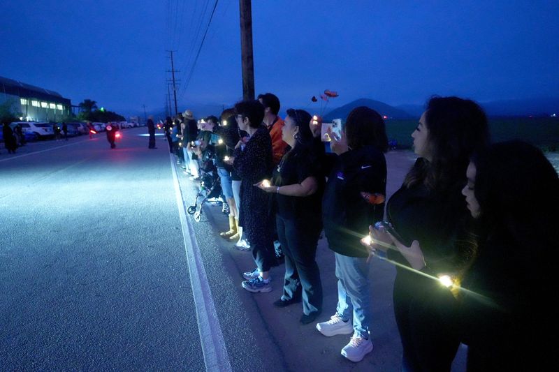 People stand in a line holding candles outside Glass House Farms in Camarillo on July 10 during a vigil that came one year after a massive immigration raid.
