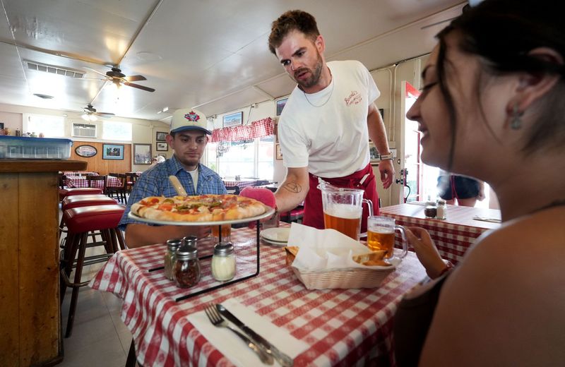 Jules Pasco, a server at Boccali's Pizza & Pasta in Ojai, places a pizza in front of Manny Fieros and his girlfriend, Esme Munoz, on July 17, 2026.