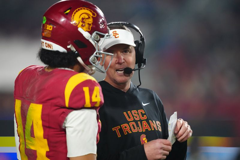 Nov 29, 2025; Los Angeles, California, USA; Southern California Trojans head coach Lincoln Riley (right) talks with quarterback Jayden Maiava (14) in the second half against the UCLA Bruins at United Airlines Field at Los Angeles Memorial Coliseum. Mandatory Credit: Kirby Lee-Imagn Images