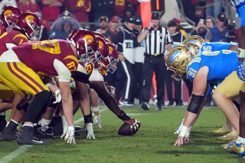 Nov 29, 2025; Los Angeles, California, USA; Helmets at the line of scrimmage as Southern California Trojans offensive lineman J'Onre Reed (50) snaps the ball against the UCLA Bruins in the second half at United Airlines Field at Los Angeles Memorial Coliseum. Mandatory Credit: Kirby Lee-Imagn Images