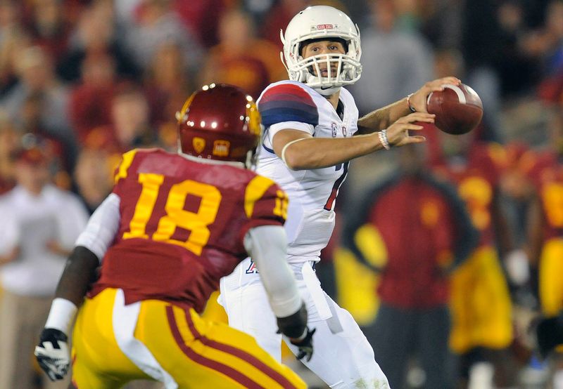 October 10, 2013; Los Angeles, CA, USA; Arizona Wildcats quarterback B.J. Denker (7) comes under pressure from Southern California Trojans safety Dion Bailey (18) during the first half at the Los Angeles Memorial Coliseum. Mandatory Credit: Gary A. Vasquez-USA TODAY Sports
