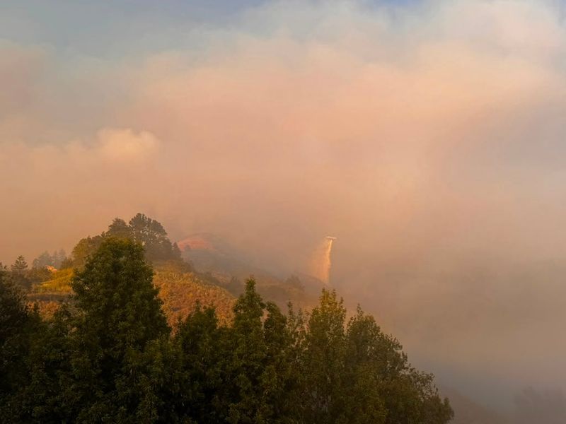 A helicopter makes a water drop over steep terrain on Aug. 10, 2026.